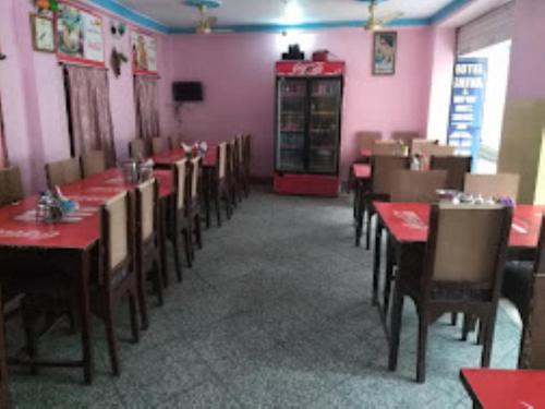菩提伽耶Hotel Shiva , Bodh Gaya的用餐室配有桌椅和粉红色的墙壁