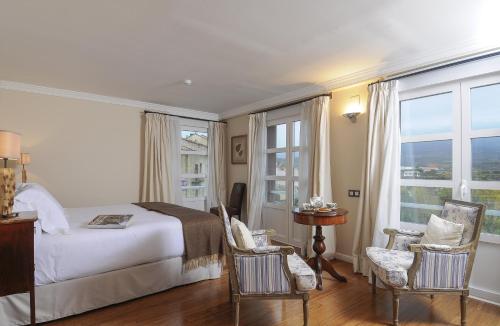 圣比森特德拉松谢拉卡索纳德尔博蒂卡里奥酒店的一间卧室配有一张床、椅子和窗户。