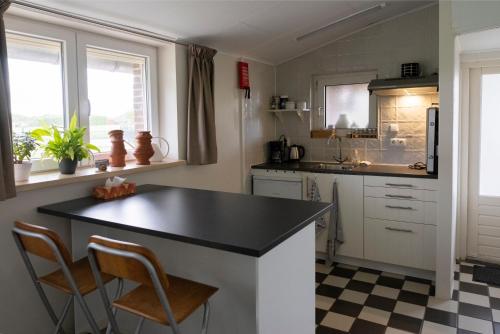 韦尔特Op d'n Stolberg的厨房配有黑色柜台和2把椅子