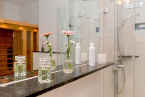 塞巴特阿尔贝克Villa Louise Nr 05的浴室柜台有三个花瓶,里面装有鲜花
