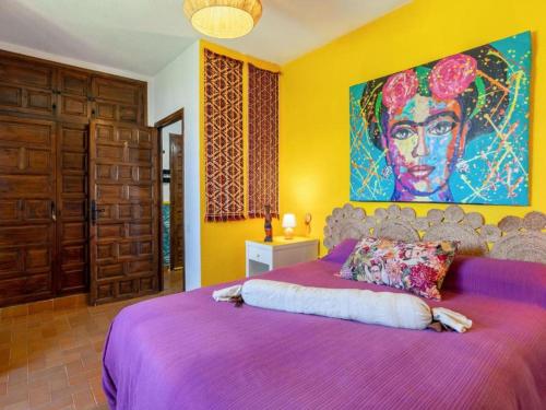雷塔马尔VIVA la FRIDA KAHLO的一间卧室配有一张紫色床,墙上挂着一幅大画