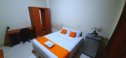 科贾扬Residence Duksina 2 By Shm的一间卧室配有一张带橙色枕头的床和一张书桌