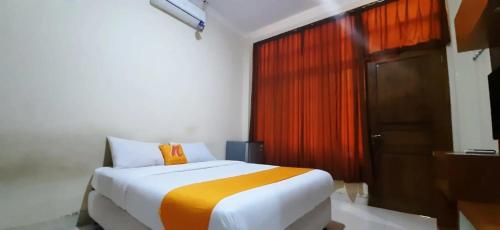 科贾扬Residence Duksina 2 By Shm的一间卧室配有一张带橙色枕头的床和一扇门