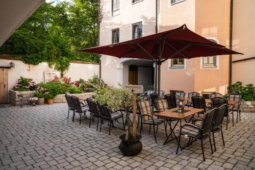 贝兴Zum Dallmayr Hotel Garni的庭院配有桌椅和遮阳伞。