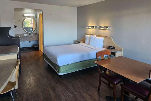 Thousand PalmsRodeway Inn & Suites Thousand Palms - Rancho Mirage的酒店客房配有一张床铺和一张桌子。