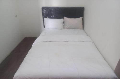 普禾加多OYO 93505 Harvest Inn Syariah的一张带黑色床头板和白色枕头的白色床