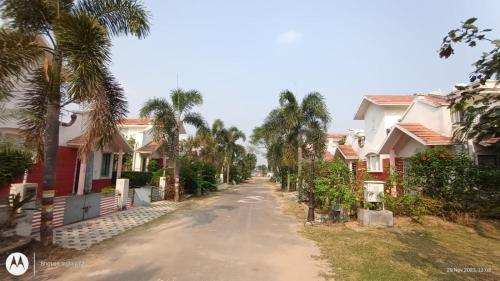 博尔普尔Raj Kuthir Homestays - Sobuj Potro的一条空的街道,有房子和棕榈树