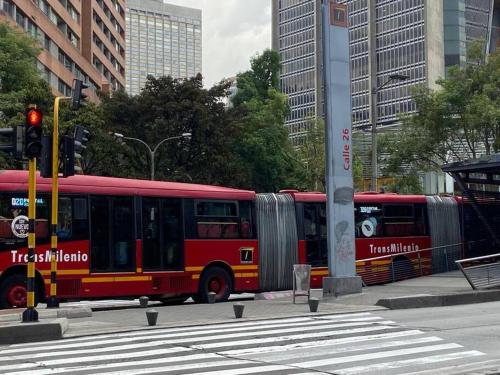 波哥大Apartaestudio Bogotá Colombia的一辆红色的巴士沿着城市街道行驶