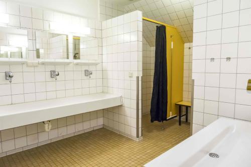 胡苏姆Jugendherberge Husum的白色瓷砖浴室设有水槽和镜子