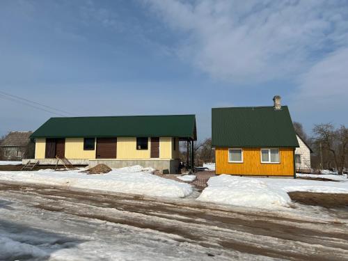 卢扎Brīvdienu namiņš的雪中带绿色屋顶的黄色房子