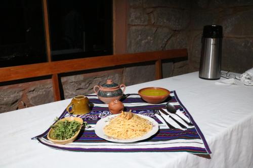 HuillanopampaBLUE SKY Lodge Taquile的一张桌子,上面放着一盘面食和蔬菜
