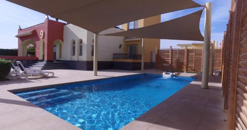 Al ḨafāʼirUtopia Villas - Ain Soukhna的房屋前带遮阳伞的游泳池