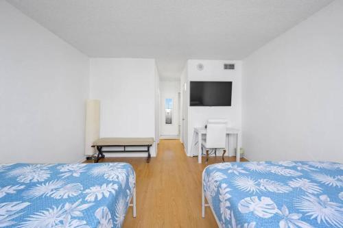 阳光岛滩Ocean View 15th floor Apartment Sunny Isles的客房设有两张床、一张桌子和一台电视机。