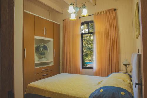 本图贡萨尔维斯Sítio Vale dos Vinhedos的一间卧室配有带橙色窗帘的床和窗户