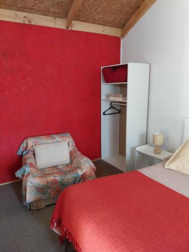 蒙特港Cabañas el Rombo的卧室设有红色的墙壁、一张床和一把椅子