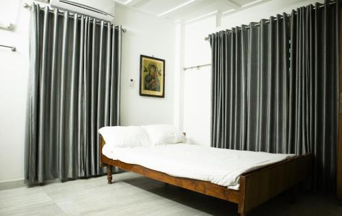 德里久尔Urban Oasis Homestay: AC Bedrooms的黑白窗帘间的一张床