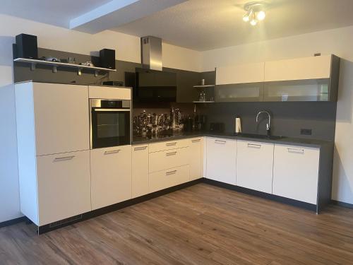 奥尔斯贝格瓦德索赫度假公寓的一间铺有木地板的大厨房,配有白色的橱柜