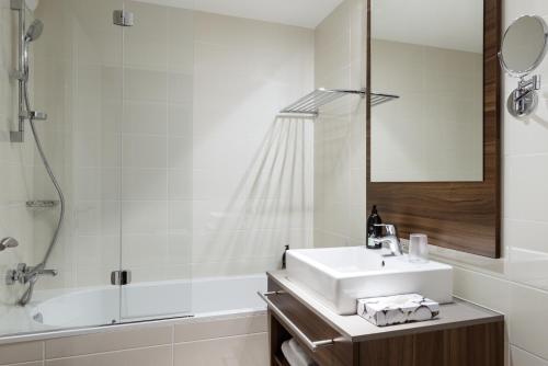 库尔布瓦拉德芳斯库尔布瓦阿德吉奥公寓式酒店的白色的浴室设有水槽和淋浴。