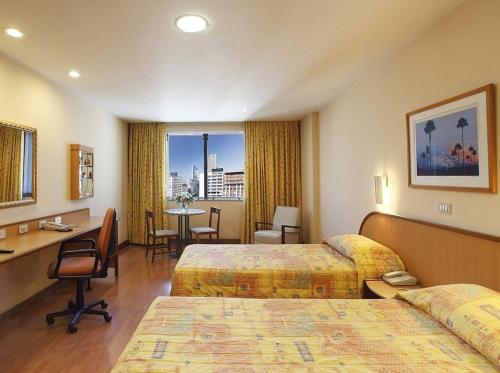里约热内卢Windsor Guanabara Hotel的酒店客房配有两张床和一张书桌