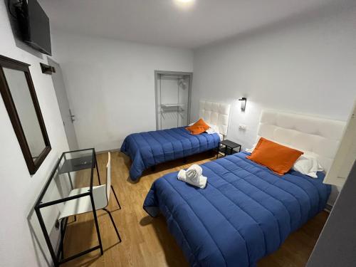 普奇塞达Hostal ARS的配有两张床铺的蓝色床单和橙色枕头