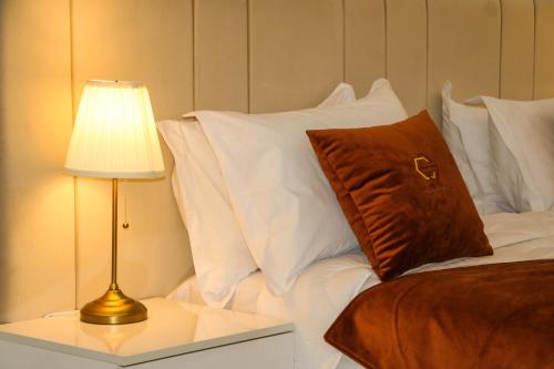 达赫拉Hotel Golden Sunset Dakhla的一张带白色枕头的床和一张带台灯的桌子