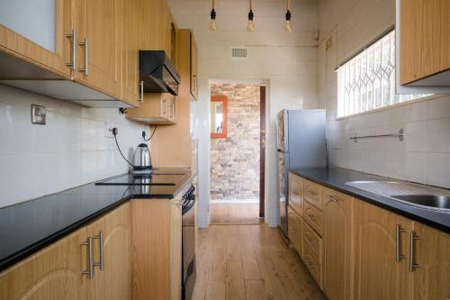 哈拉雷Hillview Holiday Condo的厨房配有木制橱柜和冰箱。