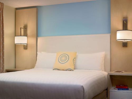 伯灵顿波士顿伯灵顿ES套房圣淘沙集团酒店的卧室配有一张带两个灯的大白色床