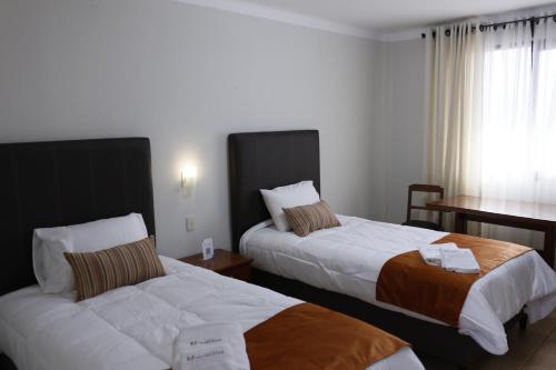 苏克雷Hotel Qhawarina de Casas Kolping Bolivia S.R.L.的酒店客房配有两张床和一张书桌