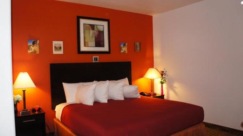 Three RiversLux Inn and Suites的酒店客房,配有一张橙色墙壁的床