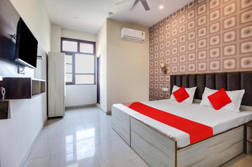 卢迪亚纳Super OYO Hotel Sky Orchid的一间卧室配有一张带红色枕头的床和电视。