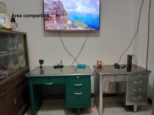 瓜亚基尔Acuarela del Rio H#3 Cerca Aeropuerto y Terminal Habitación privada con baño的客房设有书桌和墙上的电视。