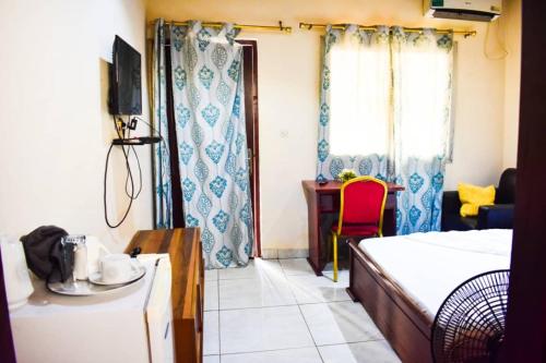 班基Appartement/Studio meublé a Bangui的一间卧室配有一张床、一张书桌和一个窗户。