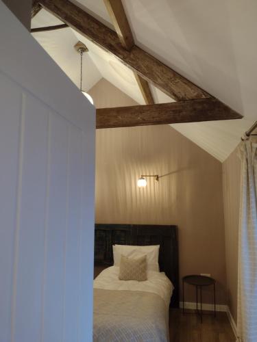 德斯利The Cow Byre - Cotswold retreat with hot tub的一间卧室设有一张床和木制天花板