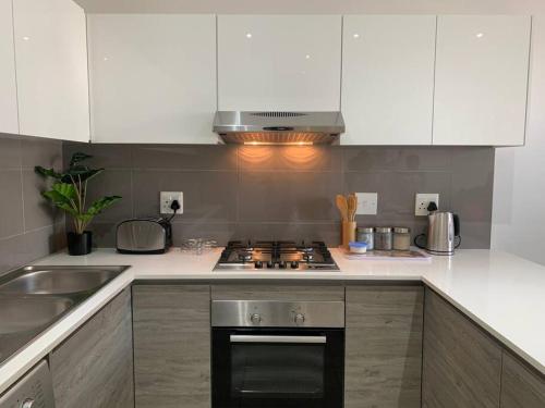 约翰内斯堡Modern Exec 2Bed Apartment at Infinite的厨房配有白色橱柜和炉灶烤箱。