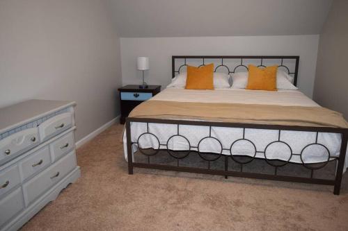 格林维尔Home In Greenville 4 bedrooms, 4 beds, 2 baths的一间卧室配有带橙色枕头和梳妆台的床