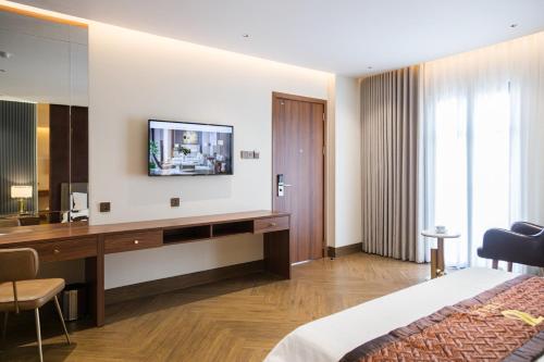 Cao LãnhHotel Trí Lê PREMIER的酒店客房设有一张桌子和一台墙上的电视。