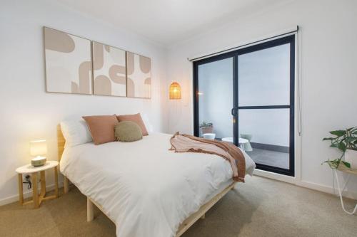 墨尔本'Laidback Lygon' A Two-storey Inner-city Oasis的一间卧室设有一张床和一个大窗户