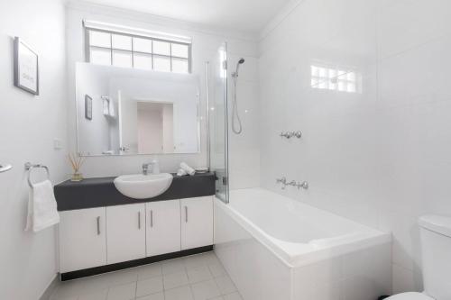 墨尔本'Laidback Lygon' A Two-storey Inner-city Oasis的白色的浴室设有水槽和淋浴。