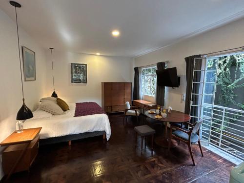 墨西哥城Roma Deco Suites的一间卧室配有一张床、一张桌子和一张桌子