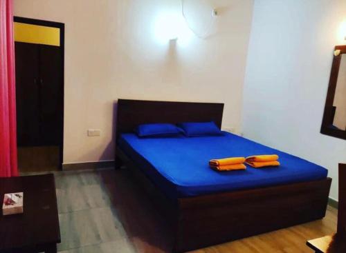 尼甘布mandodari的一间卧室配有一张带蓝色床单和橙色枕头的床。