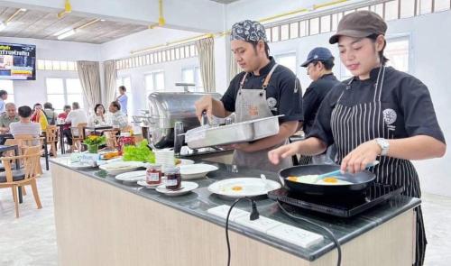 Ban ThurianBBVC Hostel - CollegeStay的两个男人在餐厅厨房准备食物