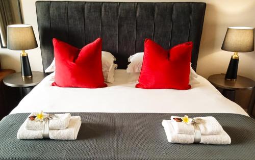 比勒陀利亚Menlyn Maine Residences - Paris king sized bed的一间卧室配有一张大床、红色枕头和毛巾。