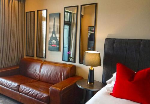 比勒陀利亚Menlyn Maine Residences - Paris king sized bed的客厅配有棕色真皮沙发和灯具