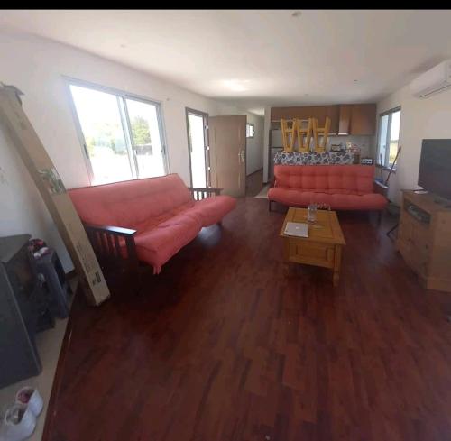 特立尼达岛Casa de Campo acogedora的客厅配有两张红色的沙发和一张桌子