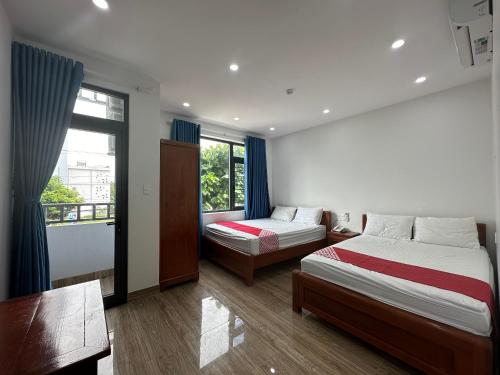 岘港OYO 1224 Motel Phuong Linh的一间卧室设有两张床、一张桌子和一个窗口。