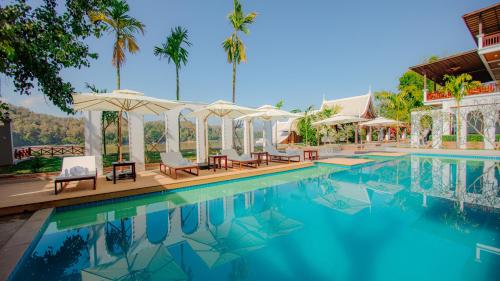 琅勃拉邦Relaxful Hotel泊岸酒店的度假村的游泳池,配有椅子和遮阳伞