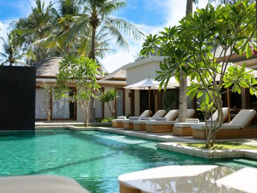 吉利特拉旺安Cocana Resort Gili Trawangan的一个带躺椅的游泳池以及别墅