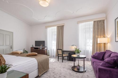 捷克克鲁姆洛夫Bellevue Hotel Český Krumlov的酒店客房设有一张床和一张紫色沙发