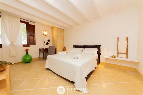 莱切省卡瓦利诺Masseria Tenuta Le Menze的卧室配有白色的床和桌子