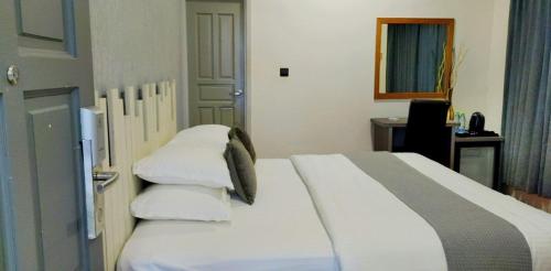 达拉万度Turtle Inn Dharavandhoo的卧室配有带枕头的白色床和书桌。